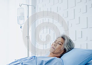 Asian senior woman patient grey hair sleeping on bed in modern white hospital room.