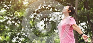 Asian senior woman in pink shirt breathing fresh air at the park while exercising