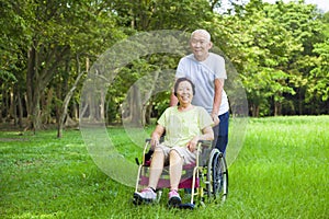 Asian senior woman sitting on a wheelchair with his husband