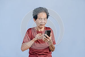 Asian senior woman smiles and video call isolated in grey background. Strong elderly grandmother feeling happy using mobile cell