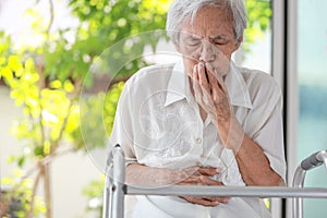 Asian senior woman with stomachache,old elderly holding her abdomen,covering mouth with hand,discomfort in the stomach associated