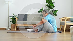 Asian senior woman stretching for exercise and workout at home. Active mature woman doing stretching exercise in living room.