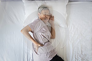 Asian senior woman suffering from backache,sore waist while sleep,unhappy old elderly feeling discomfort pain in her back muscles