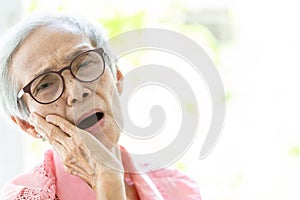 Asian senior woman suffering from toothache,tooth decay,feeling pain,female elderly people holding her cheek with hand,teeth