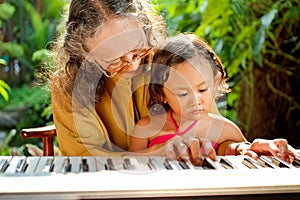 Asian senior woman teach child playing piano