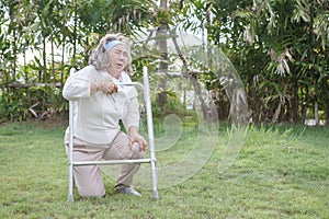 Asian Senior woman try to walking with walker falling in garden park and having knee pain. kneel Arthritis pain concept. old