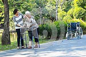 Asian senior woman use walking aid during rehabilitation after knee surgery, young carer assisting reassuring elderly people
