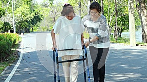 Asian senior woman use walking aid during rehabilitation after knee surgery, young carer assisting reassuring mature elderly peopl