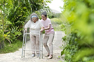 Asian senior woman walk with pian by walker, she living with Asian female physical therapist nurse take care photo