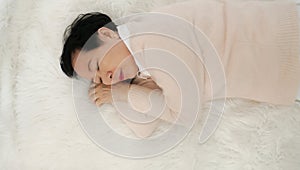 Asian senior woman wear pink sweater sleep on white fur bed