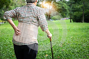 Asian senior woman wearing back support belt for protect her back pain,muscle injury,elderly people hand touching on the hip