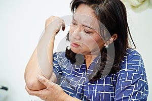 Asian senior woman wearing elastic support elbow brace for reduce pain