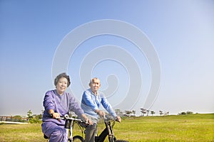 Asian seniors couple biking in the park