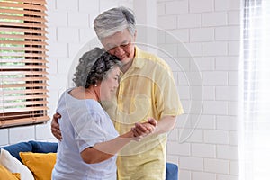 Asian seniors couple enjoy dancing in living room at home.aging at home concept