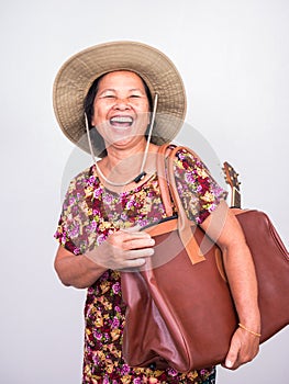 Asian senoir woman laughing while carrying ukulele and big brown