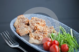 Asian sesame chicken dish on a plate with garlic sprouts