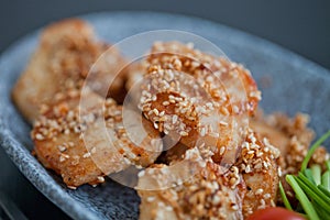 Asian sesame chicken dish on a plate with garlic sprouts