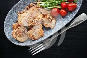 Asian sesame chicken dish on a plate with garlic sprouts