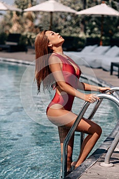 Asian sexy woman In burgundy bikini at swimming pool on a sunny day,bright tone,