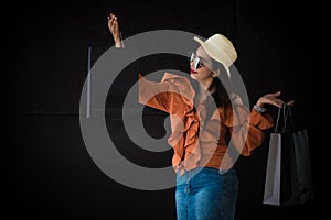 Asian shopping woman enjoy with Black Friday shopping bag on black background. Shopaholics and beauty fashion theme.