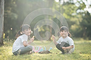 Asian sibling planting young tree on black soil together as save world in garden on summer day. Planting tree. Childchood and