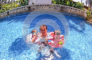 Asian sibling sisters playing in swimming pool with family in a hot summer day. Family lifestyle in vacation