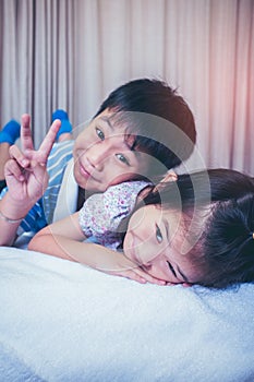 Asian siblings smiling and having fun in bedroom. Vintage tone.