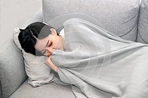 Asian Sick woman covered with a blanket lying in bed with high fever and a flu.