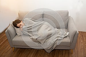 Asian Sick woman covered with a blanket lying in bed with high fever and a flu