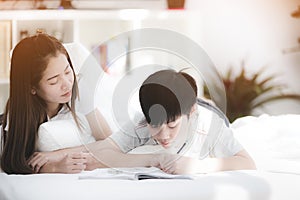 Asian sister and brother relaxing and playing on ther bed.