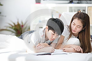 Asian sister and brother relaxing and playing on ther bed.