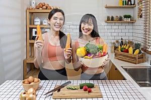 Asian sister is having a healthy food and drink while helping each other cooking in kitchen for vegan, vegetarian and plant based