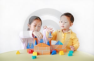 Asian sister and her little brother playing wood block toy together. Little Boy and girl doing activity over white background