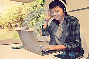 Asian sitting , student wearing headphones listening online studying course learning a book on laptop. E-learning Education