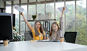 Asian smart Office or businesswoman excited successful business people, celebrating win. Two businesswoman looking at a monthly