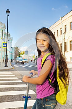 Asian smiling girl on scooter near crossroad