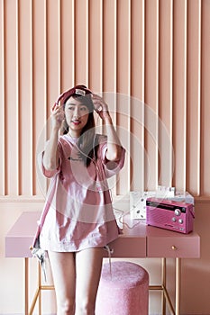 Asian smiling girl  sitting on pink working desk  with oldrose wooden stripe painted wall / cozy interior / portrait studio /fashi