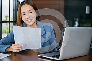 young business woman reading report document compare with laptop computer