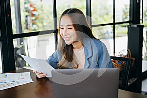 young business woman reading report document compare with laptop computer