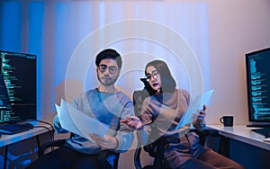 Asian software developers teams working on multiple screens displaying code and application diagrams at night in modern office