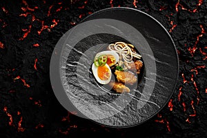 Asian soup with noodles ramen, with miso paste, soy sauce, greens and chicken. On a black stone background. top view