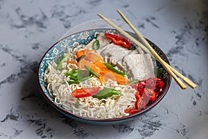 Asian soup with wheat noodles, slices of meat, red chili peppers.