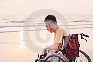 Asian special child on wheelchair on the sea beach with sunset on travel