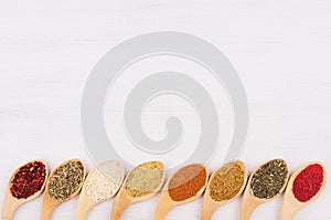 Asian spices in wooden quaint spoons on soft white board.