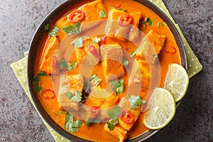Asian spicy coconut tomato fish curry closeup on a plate. Horizontal top view