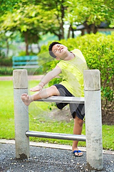 Asian sport boy stretching on iron bar in garden