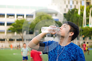 Asian sport man is drinking fresh water in transparent plastic b