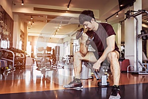 Asian sport man lifting dumbbell at fitness bench with gym equipment background. Sport exercise and People lifestyles concept