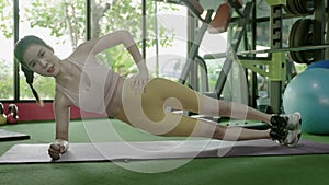 Asian sports girl doing plank side pose to work out the mid-body strength, conceptual health exercise