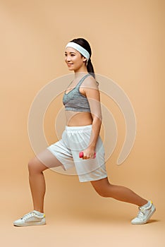 Asian sportswoman with dumbbells doing lunges